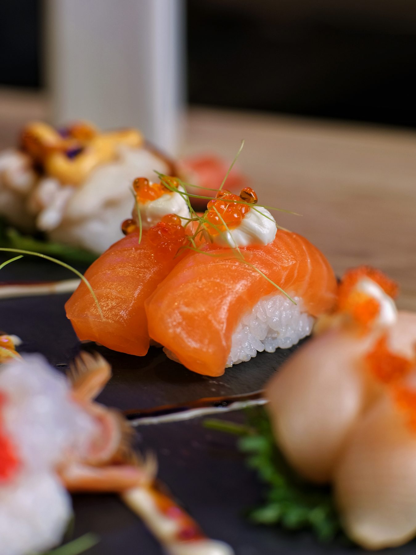 Le mani dello chef che compongono un nigiri al banco del sushi.